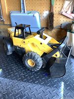Side view of vintage Tonka truck loader showing front bucket and handle mechanism.