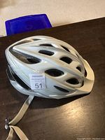 Top side view of the white bike helmet showing vent holes and chin strap.