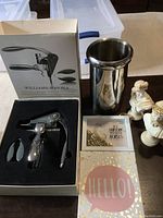 Photo showing Williams-Sonoma wine opener set in open box with additional accessories, stainless steel wine cooler, two small white bust figurines, two decorative signs.