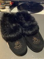 Top and side view showing black rabbit fur trim and beaded decorative design on toes.