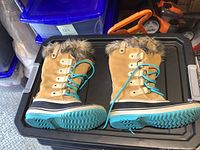 Side and top view showing tan suede boots with turquoise laces and faux fur upper trim
