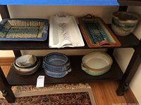 Three rectangular platters and one round lipped bowl on upper shelf