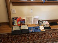 Photo showing the full lot including maps, coin holders, a jar of foreign coins, and assorted foreign paper currency notes along with some travel books.