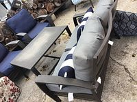 Photo showing loveseat with gray cushions, two navy blue and white striped accent pillows, and matching metal coffee table