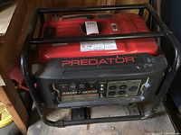 Front angled view of Predator portable generator showing control panel with multiple outlets and wattage ratings.