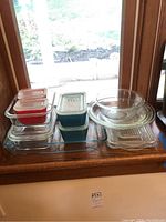 Multiple Pyrex glass baking and storage dishes displayed on a wooden window ledge