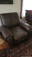 Front angle of the brown leather armchair recliner showing the seat, armrests, and cushion condition.