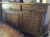 Front view showing entire antique wooden sideboard with two drawers and two doors, distressed finish and metal ring pulls.