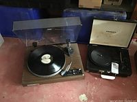 View showing both Crosley and Kenwood turntables side by side on floor, Crosley closed dust cover, Kenwood turntable closed dust cover.