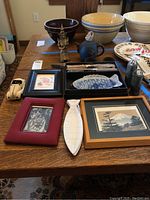 Full view of lot on table showing toy car, teapot, cups, chopsticks with plates, and framed prints