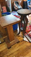Full view of both vintage wooden side tables, square and round tops, showing overall shape and surrounding environment.