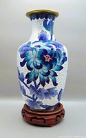 Front view of Chinese cloisonne vase on wood stand showing detailed blue floral enamel pattern and gold rim.