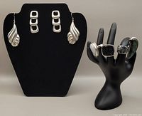 Photo showing sterling silver earrings and four rings displayed on a hand mannequin: labradorite, moonstone, abalone, and black crystal ring