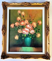 Full front photo of the original oil floral still life painting in an ornate gold decorative frame placed on flat surface.