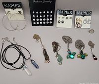 Full lot showing all jewelry items including pendants, earrings, chains with insect and seahorse pendants, and large hoop earrings.