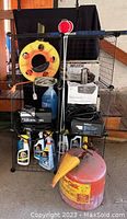 Full lot view showing wire racks, yellow extension cord reel, red plastic gas can with yellow funnel, Armor All product bottles, and boxed inflator.