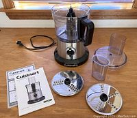 Cuisinart food processor main unit with blades and manuals laid out on table