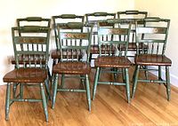 Group of eight Hitchcock chairs on hardwood floor