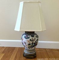 Full view of the lamp showing the white silk shade and hand-painted porcelain base.