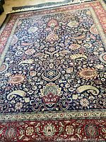 Full overhead view of rug showing tree-of-life motif on navy ground bordered in deep red