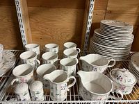 Mikasa Maxima floral china cups, creamers, sugar bowl, and salt and pepper shakers on a shelf