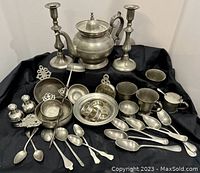 Full view of collection showing teapot, candlesticks, porringers, bowls, spoons, and other items arranged on black cloth.