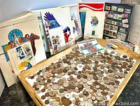 Wooden tray of mixed world coins and background showing stamp panels, album and framed display