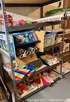 Full view of steel storage rack loaded with gift wrapping rolls, gift bags, and other supplies.