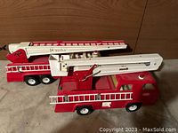 Side angle view of both trucks showing body, ladders, and wheels