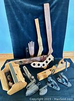 Overview photo showing wooden shoe shine kit, stretchers, irons, hand planes, and stampers arranged on black cloth.