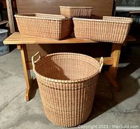 Items photographed showing the trestle workbench with three rectangular baskets on top and the large round basket with handles below.
