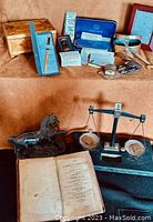 Overview of all items including rustic balance scale, metal horse, ROLLS razor kit, polemoscope, manicure set, letter openers, boxes, padlock, and book.