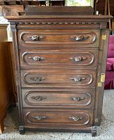 Full frontal view of the dresser showing six drawers with carved bat-shaped pull handles and the side lock panel closed.
