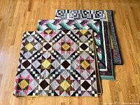 Three quilts stacked and folded on wood floor