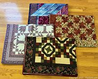 Group of four quilts overlapping on hardwood floor