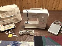 Overview of sewing machine on table with accessories and quilts partially visible