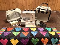 Overview of serger, cover, case, accessories, and quilt on table