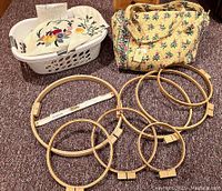 Photo showing a white laundry basket with quilting fabric scraps and applique pieces, plus wooden embroidery hoops of varying sizes and a large yellow Vera Bradley quilted bag with shoulder straps and floral pattern.