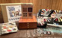 Overview photo showing wooden thread box, Cube Super Satchel box, two quilting books, folded quilt pieces with satin fan pattern, and quilting rulers.