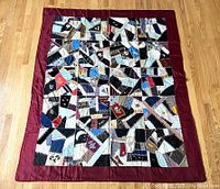 Full view of the vintage hand-stitched crazy quilt spread on floor showing entire patchwork and wine-colored silk border.
