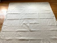 Full view of quilt spread on floor showing overall pattern and scalloped border