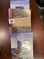 Top view of stacked photo albums showing various decorative covers including scenic and abstract designs.