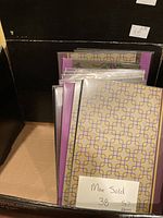 Box containing 12 new 5 x 7 albums with geometric patterned covers in plastic wrapping.