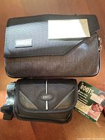 Photo of both camera cases showing Roots case with tag and Think Tank case with logo badge on front flap