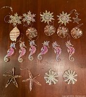 Top view showing multiple seahorse, starfish, star, and sand dollar ornaments laid out on a wooden surface.