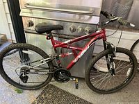 Full side view of red Rock Creek mountain bike showing frame, tires, seat, and handlebars.