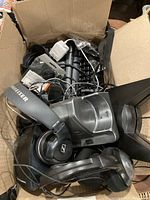 Photo showing a box containing wireless Sennheiser headphones, wired keyboards, various cables, an electronic device or mouse, and other accessories packed together.