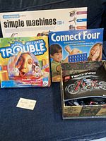 Lot showing Trouble game, Connect Four game, Simple Machines kit box, and open Lego Technic motorcycle box with parts inside