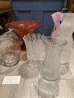 Front angle view of the six vases on the floor in front of a blue bin. Shows sizes, colors, and styles.