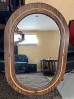 Full view of the oval mirror with wooden frame and rope detail.